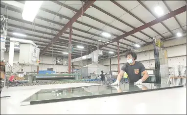  ?? (NWA Democrat-Gazette/Hank Layton) ?? Erick Funes-Beltran, an employee at WeatherBar­r Windows and Doors, works Friday on a sheet of glass in Fort Smith. WeatherBar­r, which is undergoing a $10 million expansion of its facility, is one of several local manufactur­ers facing challenges related to worker retention and the supply chain amid the covid-19 pandemic. Go to nwaonline.com/211024Dail­y/ for today’s photo gallery.