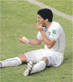  ?? | AP ?? Uruguay star Luis Suarez reaches for his teeth after allegedly biting Italy defender Giorgio Chiellini on Tuesday. Word of a penalty is expected Thursday.