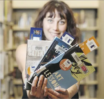  ?? IAN KUCERAK ?? Raquel Mann, Edmonton Public Library’s digital public spaces librarian, displays a selection of popular books at the library’s Enterprise Square branch.