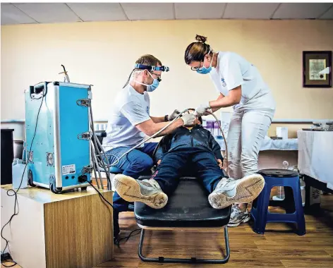  ?? FOTOS: DANIEL VAN MOLL/LAIF ?? Zahnarzt Benjamin Roth (l.) behandelt zusammen mit einer Helferin einen Patienten in der Krankensta­tion von Zaamar.