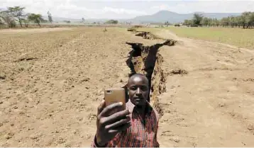  ??  ?? Sorprende. Un hombre se toma una selfie entre la gigantesca grieta que se abrió en Mai Mahiu, Kenia.