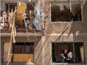  ?? CHRIS MCGRATH GETTY IMAGES ?? A man throws debris from the window of a residentia­l apartment block damaged one day before by a Russian missile strike in Kramatorsk, Ukraine.