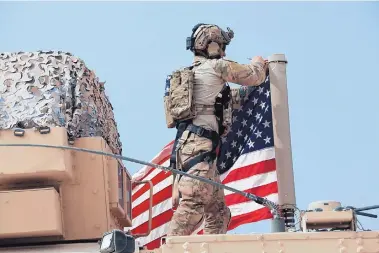  ?? BADERKHAN AHMAD/ASSOCIATED PRESS ?? American soldiers mount the U.S. flag on a vehicle Sunday near the town of Tel Tamr, north Syria, where Kurdish-led fighters and Turkish-backed forces clashed amid efforts to work out a Kurdish evacuation from a border town.