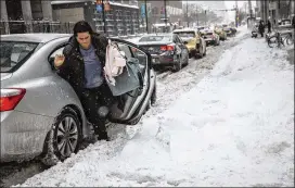  ?? RICH HEIN / CHICAGO SUN-TIMES ?? A woman exits a car during a snowstorm Friday in Chicago, where Mayor Rahm Emanuel said the city was gearing up for three more rounds of snow through the weekend after crews dealt with 6 to 7 inches overnight Thursday into Friday. Slide-offs and...