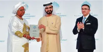  ?? Ahmed Ramzan/Gulf News ?? Shaikh Mohammad presents the Best Minister Award to Senegal’s Awa Marie Coll-Seck as George Atalla, Partner at Ernst and Young, looks on.