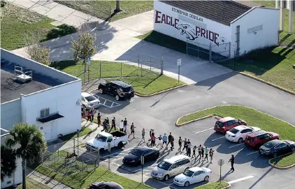  ?? Mike Stocker/Sun Sentinel/TNS ?? ■ Students are evacuated by police out of Stoneman Douglas High School in Parkland, Fla., after a shooting on Feb. 14. According to testimony, the death toll was higher because a security recommenda­tion was ignored.