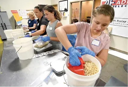  ?? STAFF PHOTO BY MATT HAMILTON ?? From left, Linda Bradford, Martha Carpenter, Caroline Carpenter and Abigail Carpenter sort bulk elbow pasta into 16-ounce bags at the Chattanoog­a Area Food Bank on Tuesday.