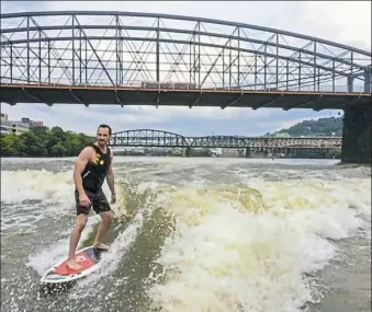  ??  ?? Duff Cooper wakesurfs on the Monongahel­a River during one of Matt Broley’s free Pass the Handle events.