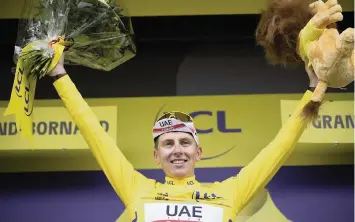  ?? CHRISTOPHE ENA AP ?? New overall leader Tadej Pogacar celebrates on the podium after the Tour de France’s eighth stage Saturday.