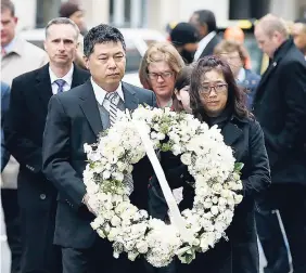  ?? AP ?? The father of Lingzi Lu, Jun Lu (foreground left) and her aunt Helen Zhao (foreground right) carry a wreath ahead of the family of Martin Richard (background from left), Henry, Bill, Denise and Jane (partially hidden) during a ceremony at the site...