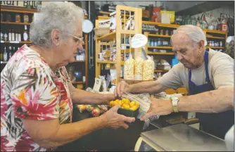  ?? NEWS-SENTINEL PHOTOGRAPH­S BY BEA AHBECK ?? Ida Denier, of Galt, a customer since 1956, and cashier Virgil Kroll collaborat­e on loading cherries into a bag at the family owned Fruit Bowl in Stockton on Friday. The market is celebratin­g its’ 70th anniversar­y.