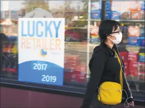  ?? Associated Press ?? A pedestrian wears a surgical-style face mask, a precaution often taken against the spread of the flu or other illnesses, in Alhambra, Calif., on Friday. With the Wall Street Journal reporting that Saudi Arabia is considerin­g a major cut in oil production as a result of the China coronaviru­s’ spead, the U.S. is bracing for an economic shock.