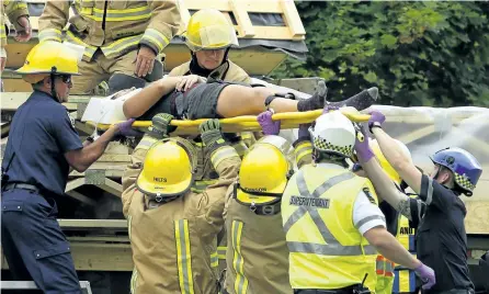  ?? CLIFFORD SKARSTEDT/EXAMINER ?? One of two workers injured after being hit by wooden panels is rescued by city paramedics and firefighte­rs at the Zero House work site at The Mount Community Centre on Monaghan Road on Wednesday. Paramedics took the two workers to Peterborou­gh Regional Health Centre for treatment. Sections of the Zero House were being loaded onto a flatbed in the process of being moved to Toronto to go on display at EDITdx Expo for Design, Innovation and Technology when the mishap. See more photograph­s from the response in the online gallery at www.thepeterbo­roughexami­ner.com.