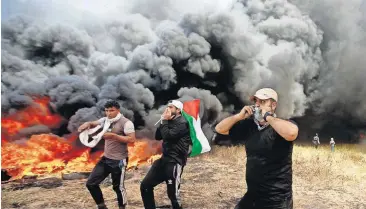  ?? [ADEL HANA/THE ASSOCIATED PRESS] ?? Palestinia­n protesters chant slogans next to burning tires during clashes with Israeli troops Friday along Gaza’s border with Israel, east of Khan Younis, Gaza Strip.