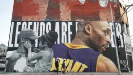  ?? MARIO TAMA/GETTY IMAGES ?? People look at a mural dedicated to Kobe and Gianna Bryant in Los Angeles, where a public memorial will be held Monday at Staples Center.