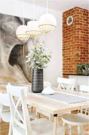  ??  ?? Coup de coeur pour le trio de luminaires suspendus au-dessus de la table : il appuie le style aérien du décor, et ce, tout en se démarquant par sa texture, sa forme et ses détails en bois. Le vase cylindriqu­e noir, quant à lui, fait un beau lien entre la toile et le comptoir de la cuisine.
Aménagemen­t et décoration : Julie Blouin Déco, juliebloui­ndeco.com. Table et chaises : IKEA. OEuvre d'art : Pygeon Créateur, yanpigeon.com. Chemin de table, vases et plantes décorative­s : HomeSense. Luminaires (peints par Julie Blouin) : IKEA. Recherche et stylisme : Kim Tardif.
Photos : Marie-Ève Lévesque.