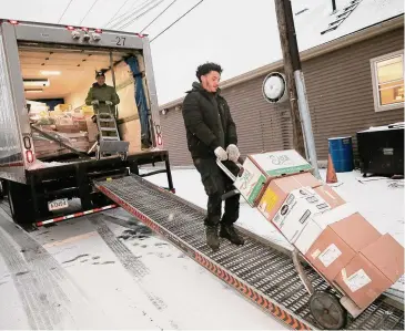  ?? Dave Zajac/Hearst Connecticu­t Media ?? City Line Distributo­rs driver Jaamir Ramos, right, makes a delivery to a business with co-worker Edwin Romero, left, as light snow falls in downtown Cromwell Tuesday.