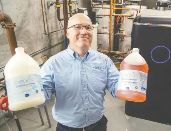  ?? MIKE DREW ?? Jaeson Cardiff, CEO of CleanO2, a small-scale carbon capture and storage device that reduces emissions from natural gas fired furnaces. He is holding jugs of soap manufactur­ed using the carbon captured in the device behind him, installed in residentia­l complex in Calgary.