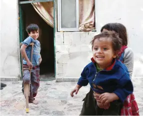  ??  ?? A Syrian boy, who suffers from severe leg injuries, plays near his siblings outside their family house in the Eastern Ghouta town of Hamouria. (AFP)