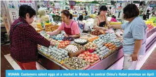  ?? ?? WUHAN: Customers select eggs at a market in Wuhan, in central China’s Hubei province on April 16, 2024. — AFP