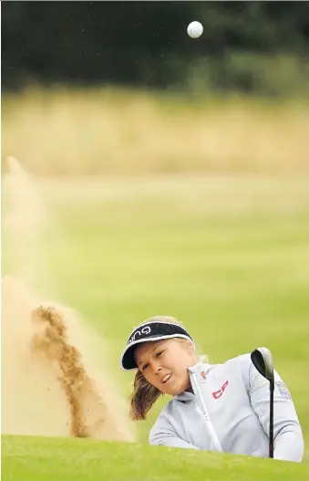  ?? ROSS KINNAIRD/GETTY IMAGES ?? Brooke Henderson of Smiths Falls, Ont., blasts out of the bunker on her way to a 2-under 70 during Friday’s second round at the Women’s British Open in Lytham St Annes, England. Henderson sits in a tie for eighth at 5 under, while Thailand’s Pornanong Phatlum had sole possession of the lead at 10 under.