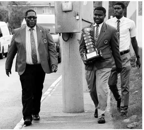  ?? FILE ?? Acting principal Calvin Rowe (left) and then head boy Rajay Maragh walk with the Mortimer Geddes Trophy on March 16, 2017.