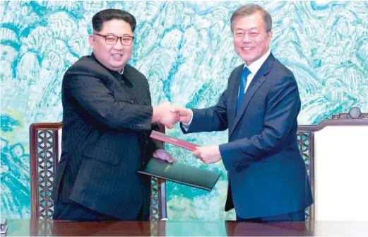  ?? AP ?? North Korean leader Kim Jong Un ( left) and South Korean President Moon Jae- in shake hands at the border village of Panmunjom in the Demilitari­zed Zone, South Korea.