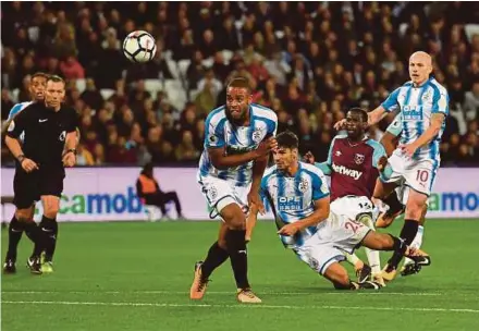 ?? AFP PIC ?? West Ham United’s Pedro Obiang (second from right) shoots and scores from a deflection off Huddersfie­ld Town’s Mathias Jorgensen (centre) during their Premier League match on Monday.