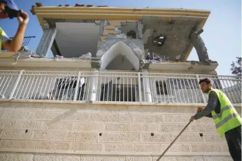  ?? — Reuters ?? Municipali­ty employees work next to a house that the Israeli military said was hit by a rocket fired from the Gaza Strip, in Beersheba, on Wednesday.