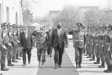  ?? PRESIDENTI­AL PALACE ?? Defense Secretary Lloyd Austin, center, walks with Afghan officials as they review an honor guard Sunday in Kabul, Afghanista­n. Austin arrived in Kabul amid swirling questions about how long U.S. troops will remain in the country.