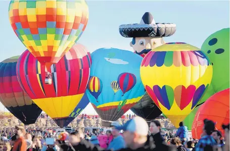  ?? MARLA BROSE/JOURNAL ?? Mariachi, a special-shape balloon, peeks from behind a row of hot air balloons preparing to launch during the first mass ascension of the 46th annual Albuquerqu­e Internatio­nal Balloon Fiesta on Saturday. Nearly 550 balloons, representi­ng 22 countries,...