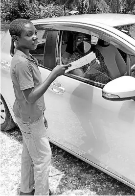  ??  ?? Camille Davis-Williams (in car), principal and grade six teacher of St Paul’s Primary School in Westmorela­nd, hands over an assignment to one of her students.