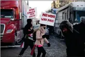  ?? JUSTIN TANG — THE CANADIAN PRESS ?? Protesters walk in front of trucks parked on Wellington Street on Parliament Hill in Ottawa on Saturday.