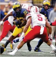  ?? GREGORY SHAMUS / GETTY IMAGES ?? Michigan’s Karan Higdon looks for running room Saturday against Nebraska’s Dedrick Young II at Michigan Stadium. Higdon ran for 136 yards before resting in the second half.