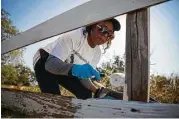  ??  ?? Jamie Williams repaints an old fence at Byrd Cemetery. Williams, a member of the Fort Bend Heritage Society, has relatives buried in the community cemetery.