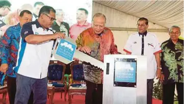  ??  ?? TUN Dr Mohd Khalil (tengah) dan Idris (kiri) menyempurn­akan perasmian Projek Kondominiu­m Sri Melaka Residensi di Taman Rekreasi Bukit Serindit.