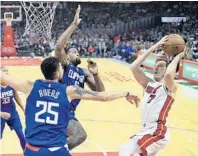  ?? MARK J. TERRILL/AP ?? Miami’s Goran Dragic, right, goes up on the baseline against Los Angeles’ Austin Rivers, left, and center DeAndre Jordan during Sunday’s win by the Heat.