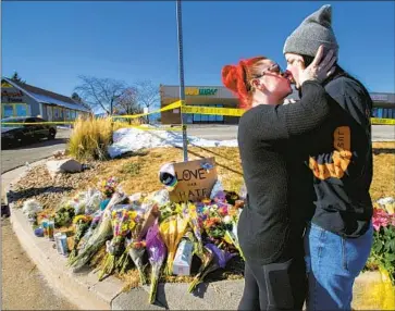  ?? Christian Murdock The Gazette ?? SOPHIE KAMERRER, left, and Torrey Lovett kiss on Sunday at a makeshift memorial near Club Q in Colorado Springs, Colo. Authoritie­s say a gunman killed five people and injured 25 others at the club on Saturday.