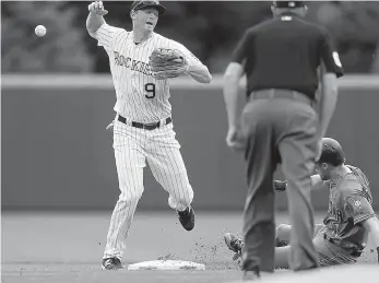  ?? AP Photo/David Zalubowski ?? Colorado Rockies second baseman DJ LeMahieu, left, loses the ball after forcing out Arizona Diamondbac­ks’ Jeremy Hazelbaker at second base, as second base umpire Chad Whitson makes the call, in the first inning Thursday in Denver.