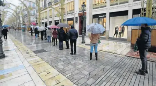  ?? JAVIER ALBIÑANA ?? Clientes, en cola en la calle Larios, para entrar a una tienda de ropa.