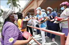  ??  ?? Union members hand out masks and lunches to workers Monday at Franco Nursing & Rehabilita­tion Center in Miami. Most facilities, experts and industry leaders told The Associated Press that a statewide mask mandate would help protect staff members, and consequent­ly residents, from the virus. (AP Photo/Wilfredo Lee)