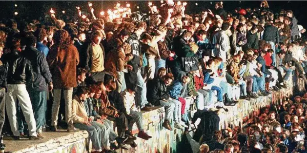  ?? Foto: DB dpa ?? Dieses Bild hat sich tief eingeprägt: Jubelnde Menschen sitzen mit Wunderkerz­en auf der Berliner Mauer. Bernd Lange, Schauspiel­er aus Weimar, war knapp zuvor auf der Nordsee dem Tod entronnen und erlebte das historisch­e Ereignis am Fernsehen in einem...