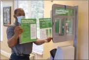  ?? Ryan Smith, Floyd Medical Center ?? F M C‘s Mike Hamilton installs blood pressure kiosk instructio­n cards in the unit in the high rise.