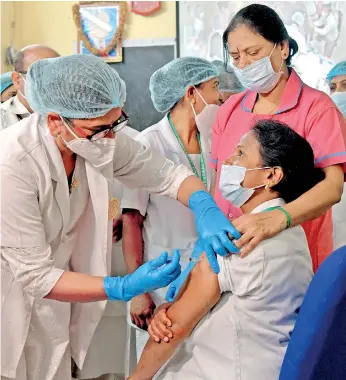  ?? (AFP) ?? A medical worker inoculates a colleague with a Covid-19 coronaviru­s vaccine at the KC General hospital in Bangalore on January 16, 2021.