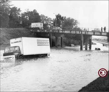  ??  ?? Another view showing the stranded Sainsbury’s lorry precarious­ly leaning over in the floods with motorists stranded further along