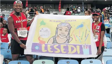  ?? / SUPPLIED ?? Bongani Buhlalu and Namhla Motsukunya­ne display the banner after the race.