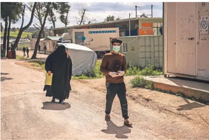  ?? FOTO: DPA ?? Ein Migrant mit einer Schutzmask­e läuft zum Eingang des Lagers Ritsona. Der griechisch­e Coronaviru­s-Krisenstab hat das Flüchtling­slager im Norden Athens mit seinen rund 3000 Bewohnern für 14 Tage unter Quarantäne gestellt.