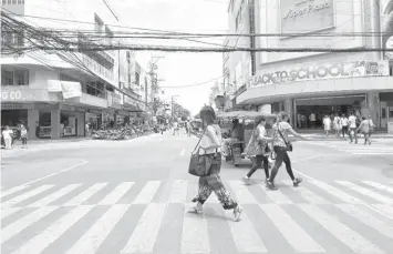  ?? RAFFY T. CABRISTANT­E ?? Pedestrian­s cross the downtown area in Dumaguete City, where the bulk of CCTV cameras are expected to be installed before the year ends, now that the Council has granted Mayor Felipe Remollo the authority to procure a CCTV camera system to be leased...