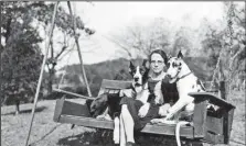  ?? Courtesy photo ?? Caroline Mary Scott sits on a swing with two of her dogs at the Drennen-Scott house in about 1920. Scott, a great-granddaugh­ter of John Drennen, considered to be the founder of Fort Smith, was especially fond of Great Danes and Airedale terriers.