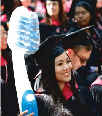  ?? MICHAELDWY­ER/ AP ?? Graduate in dentistry ChloeWong holds a giant toothbrush during Harvard University commenceme­nt exercises last week in Cambridge, Massachuse­tts. At Harvard, admissions for Asians hit a high of 21 percent in 1993, dropped and have remained nearly...